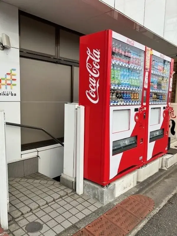 おへそキッチンのビルの入り口　コカ・コーラの自販機が目印